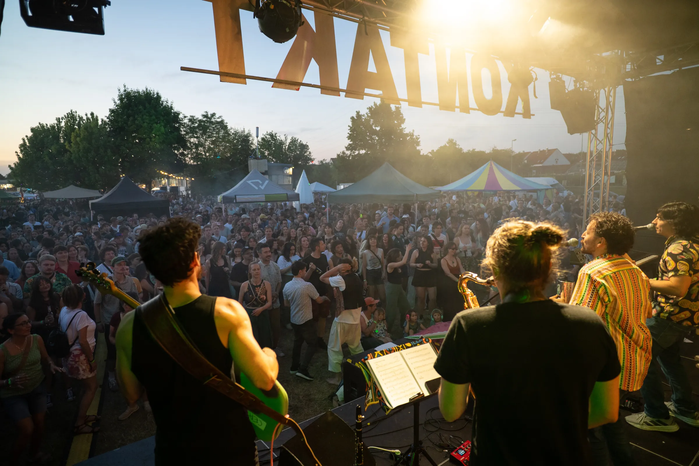 Band playing to a large festival crowd at sunset