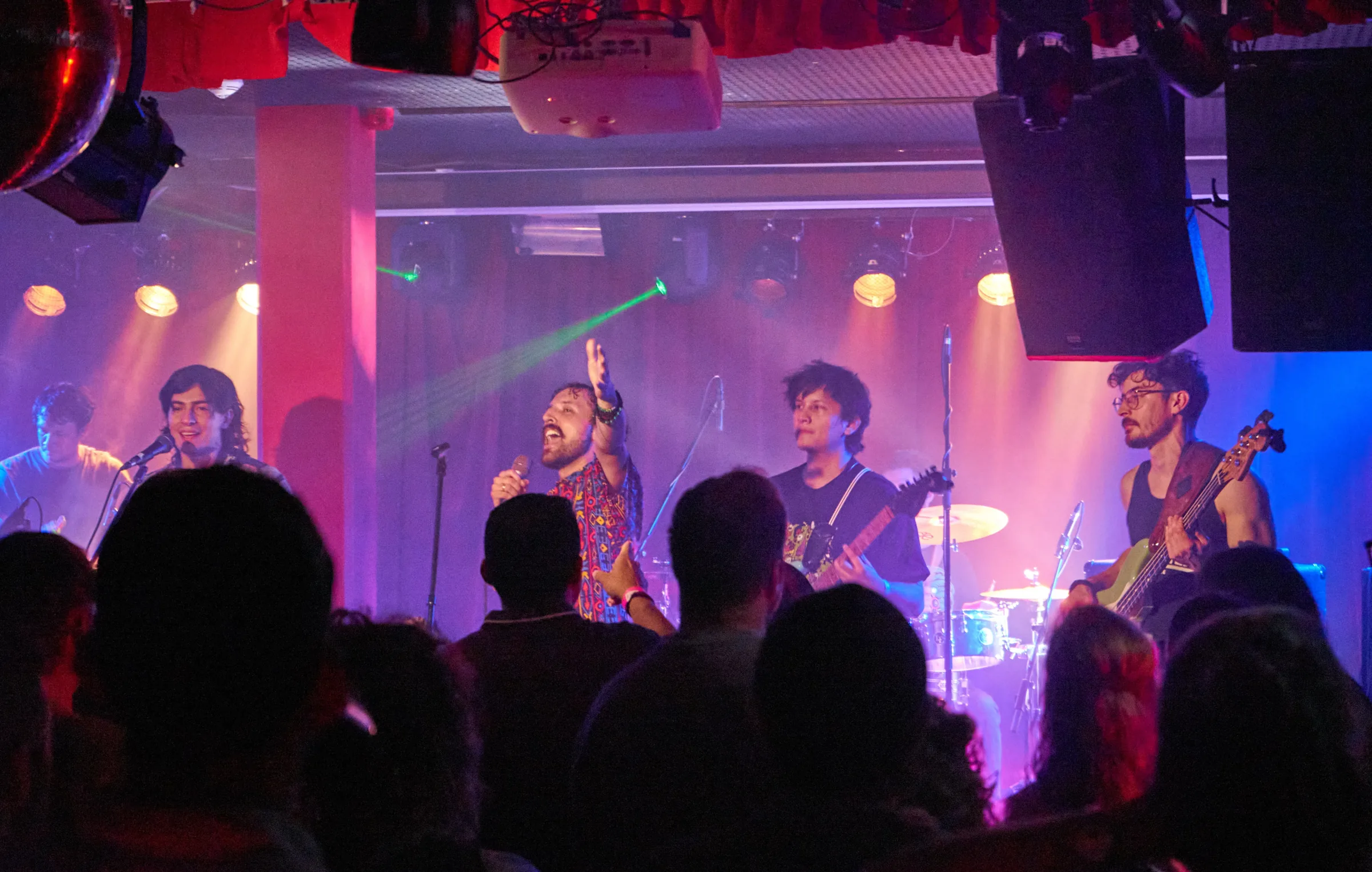 The band performing under colorful lights in front of a lively crowd