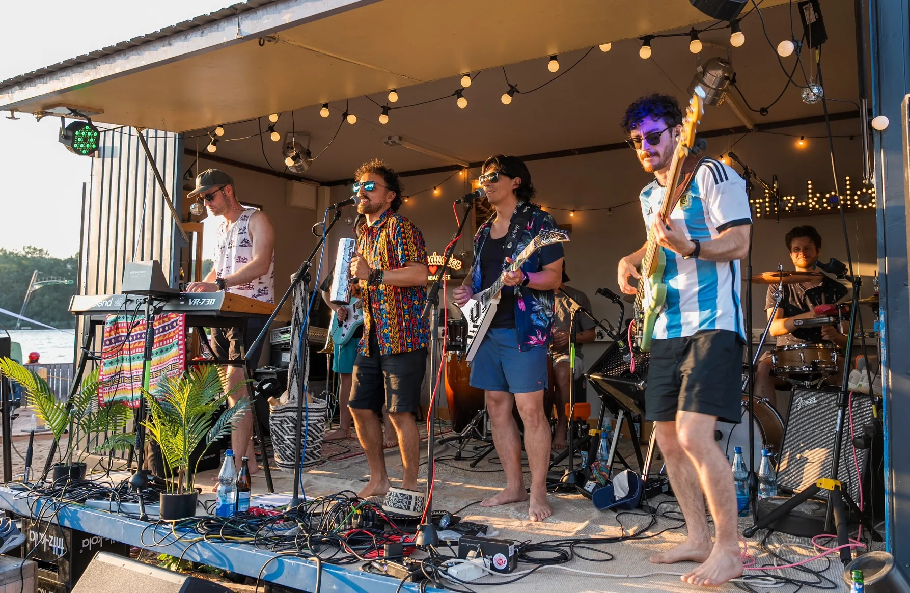 The band performing on an outdoor stage by the lake